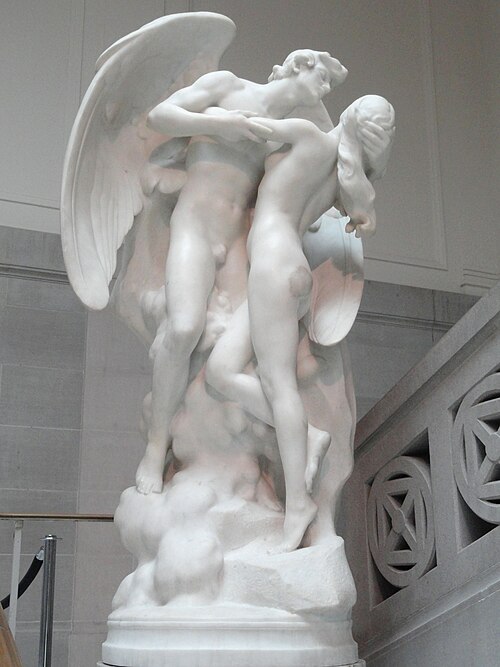 A white marble sculpture depicting a male figure with wings embracing a female figure, both in a dynamic pose suggesting movement and passion.